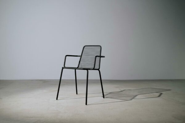 A minimalist metal chair in a studio setting casting a shadow, perfect for design concepts.